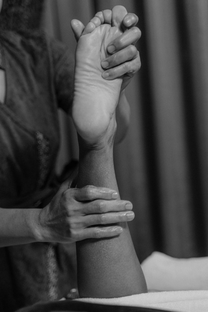 pexels photo 6188041 6188041 A black-and-white image of a massage therapist performing an ankle and foot massage.